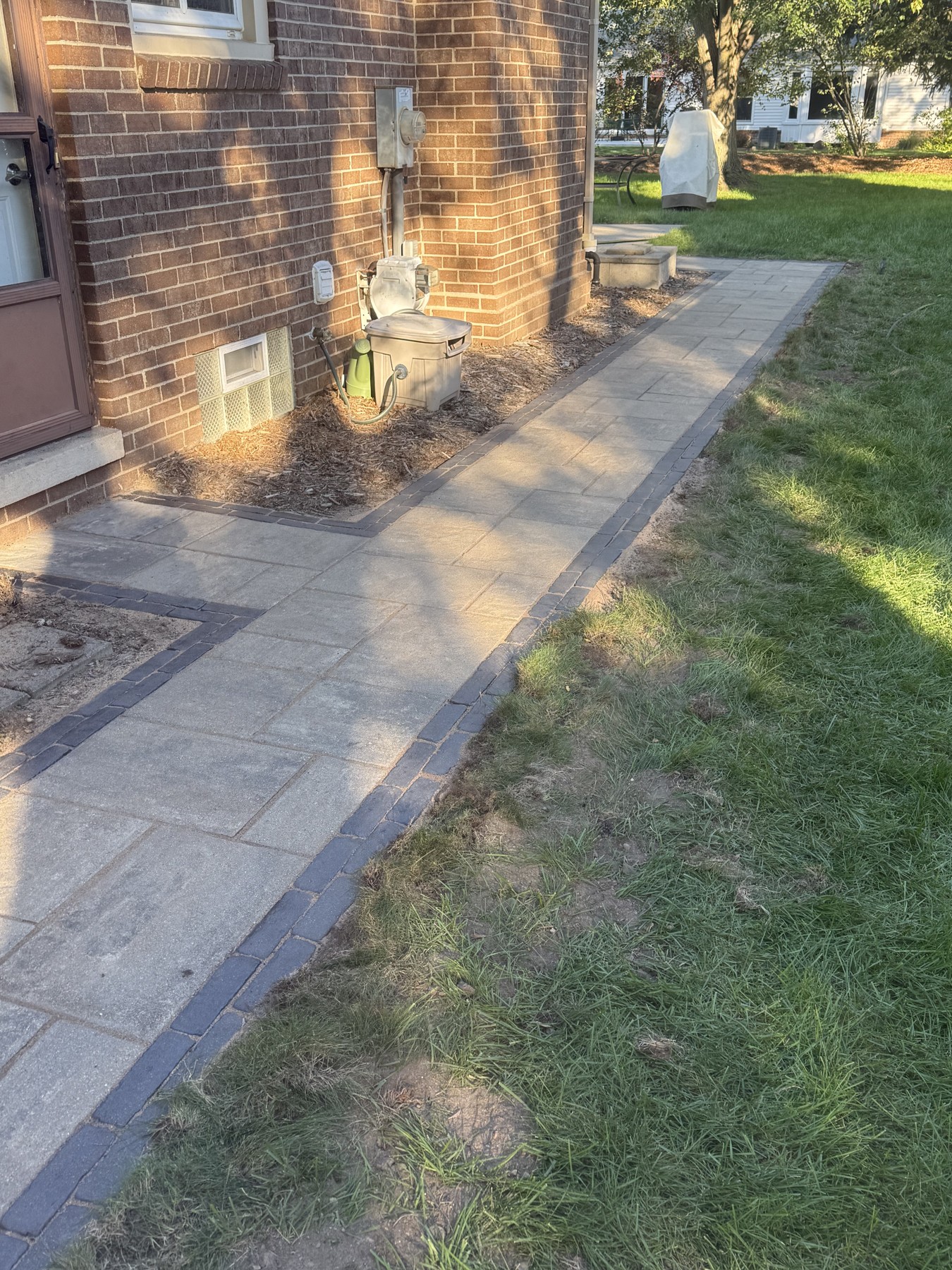 Paver sidewalk continuing along the side of a brick home